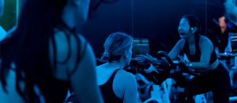 A group of people are working out on exercise bikes in a dimly lit room.