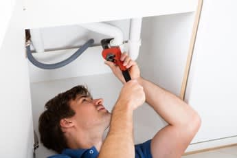 a man is fixing a pipe under a bathroom sink at Southpark on Whyte, Edmonton, Alberta, T6E 3S3