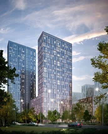 A modern glass building is surrounded by trees and has a car parked in front.