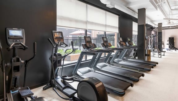 a gym with cardio equipment and a large window