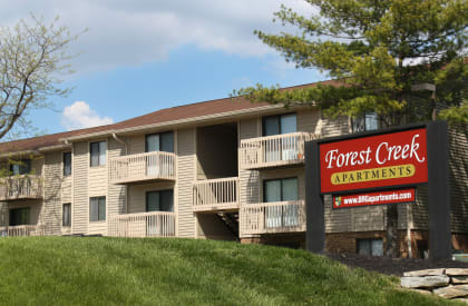 an apartment building with a forest creek apartments sign