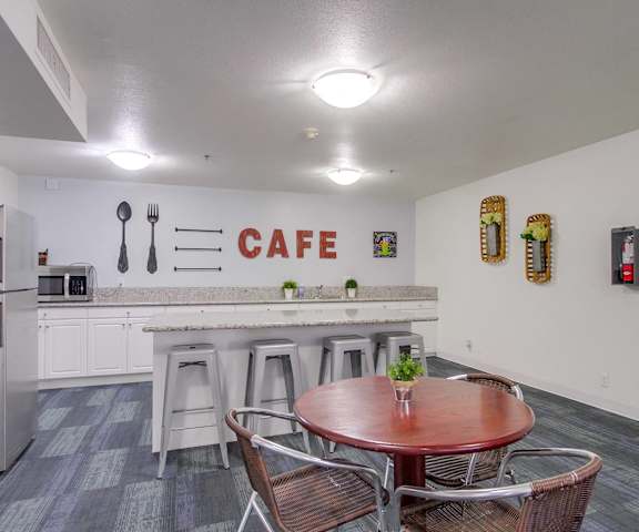 a dining room with a table and chairs in front of a kitchen with a bar
