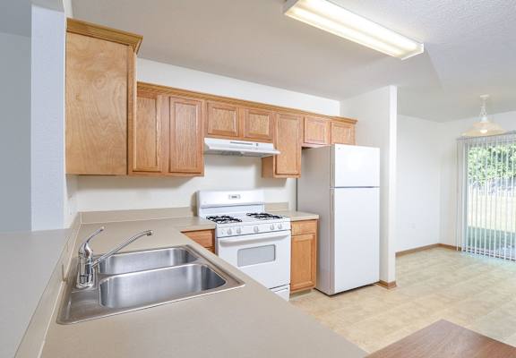 an empty kitchen with wooden cabinets and appliances and a sink