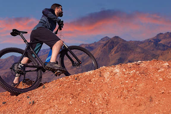 A man is riding a bike on a rocky terrain.