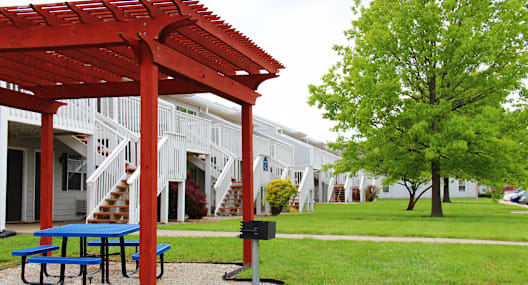 A red pergola is in front of a white building.
