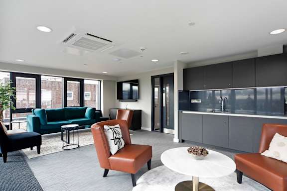 a living room with couches and chairs and a kitchen
