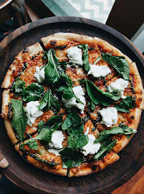 A pizza with spinach and white topping on a wooden board.at Alante Homes at Spring Run, Idaho, 83607