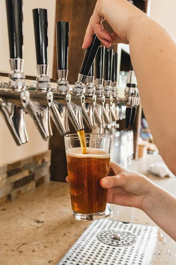 A person is pouring a dark beer from a tap into a glass.