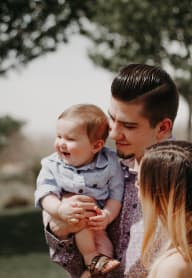 A man holding a baby while standing next to a woman. at Autumn Village, Milton, WA, 98354