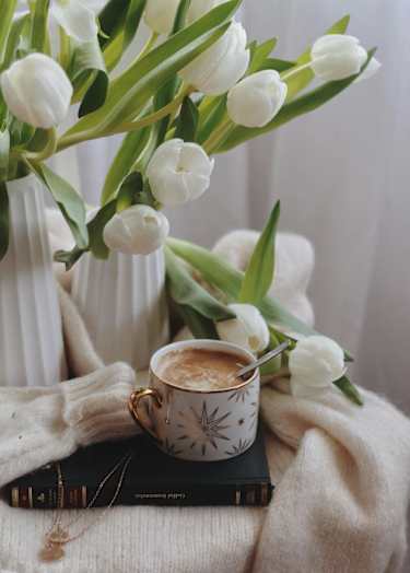 A cup of coffee with a book and a white vase with white tulips at Balfour Marietta Apartments, Marietta, GA, 30060