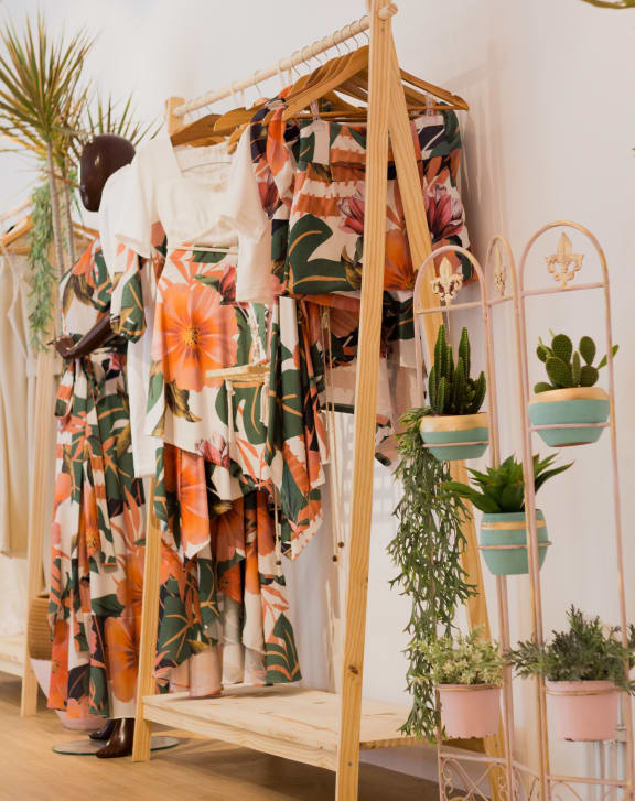 a wooden clothes rack with plants and clothes on it