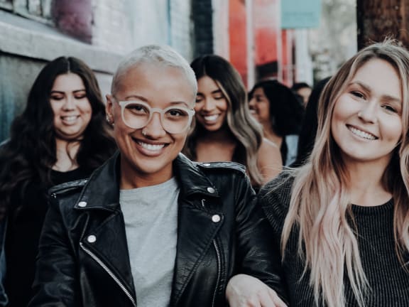 a group of women wearing leather jackets and smiling at the camera
