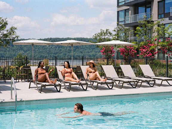 Three women sunbathing by a pool.