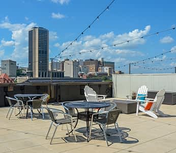 a rooftop patio with tables and chairs and a city in the background