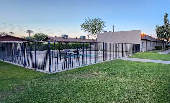 a fenced in yard with a pool and lounge chairs