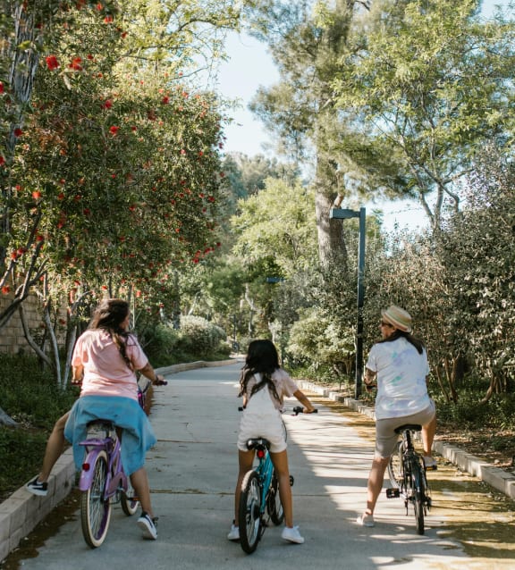 three girls riding bikes down a street