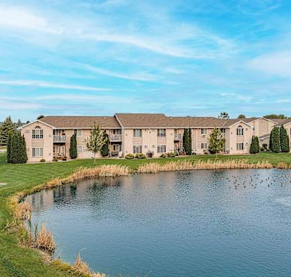 an apartment building overlooking a pond with ducks in the water