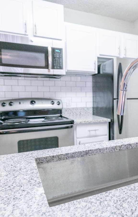 a white kitchen with stainless steel appliances and granite counter tops