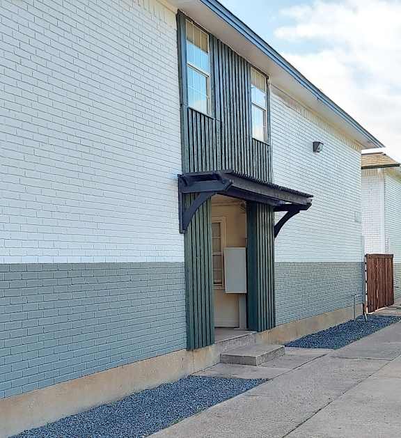a white brick building with a door with a green curtain