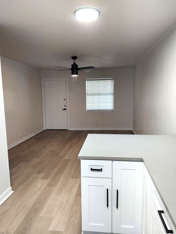 an empty kitchen with white cabinets and a ceiling fan