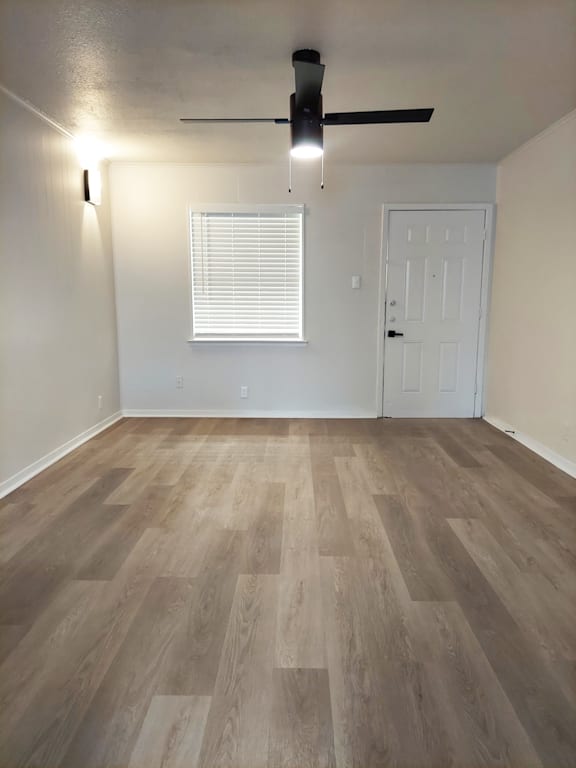 an empty living room with wood floors and a ceiling fan
