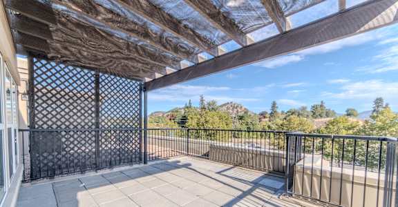 A balcony with a lattice fence and a view of trees and hills.