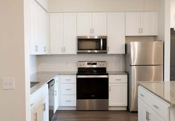 a kitchen with white cabinets and stainless steel appliances at The Crest at Laurel Canyon Apartments, Naples