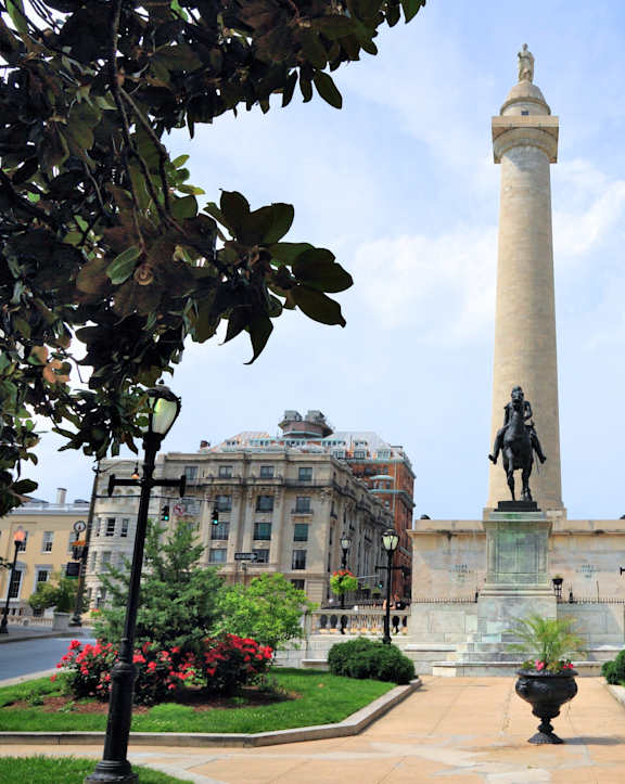 a tall column with a statue in the middle of a city street