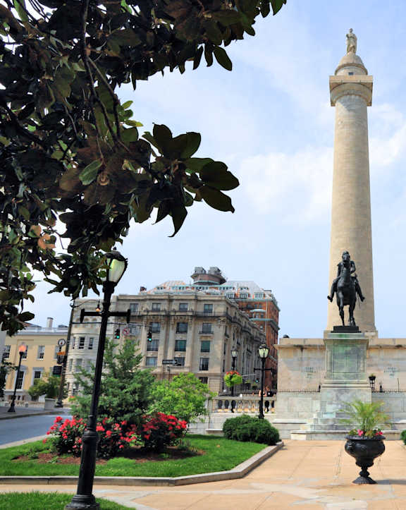 a tall column with a statue in the middle of a city street