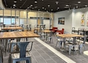Thumbnail 6 of 7 - A modern dining area with wooden tables and grey chairs.
