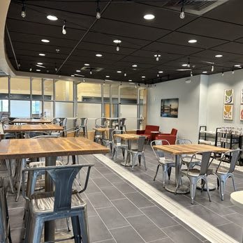 A modern dining area with wooden tables and grey chairs.