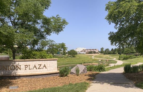 a sign that says union plaza in front of a grassy area with trees and bushes