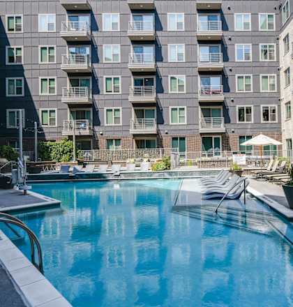 A large swimming pool in front of apartment buildings.
