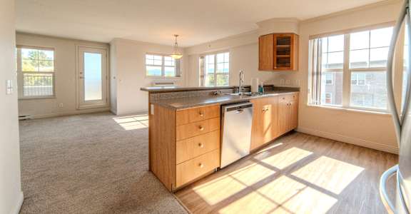 A sunny kitchen with wooden cabinets and a large island.