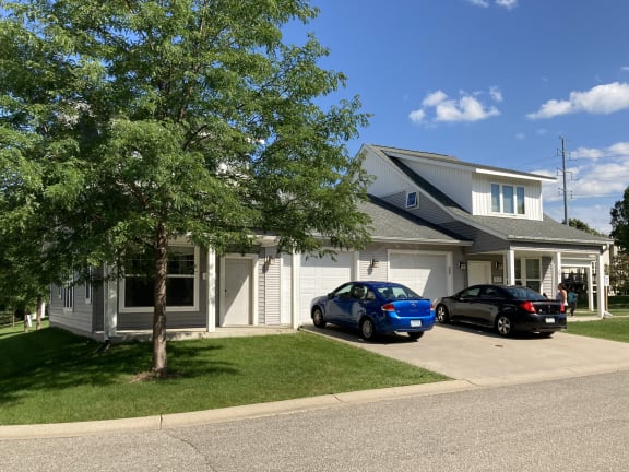 a white house with a blue car parked in the driveway