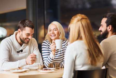 Four people are sitting at a table, enjoying a meal and drinks together.