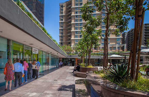 A group of people are standing outside of a building with a green roof.