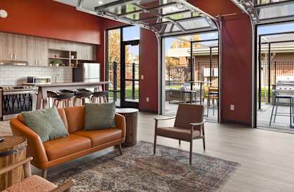 a living room with a couch and chairs and a kitchen