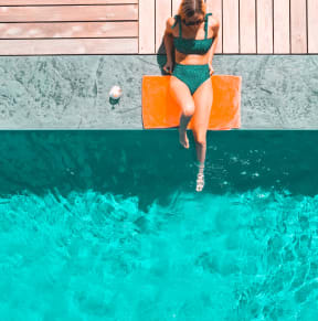 a woman in a green bikini jumping into a pool