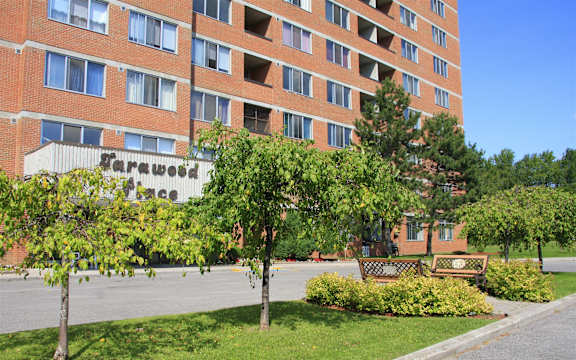 A tree in front of a brick building with the name "Farwood" on it.