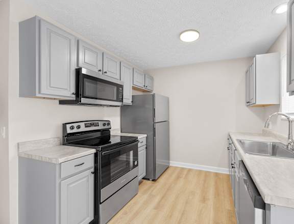 A kitchen with a stove, oven, refrigerator, and microwave.