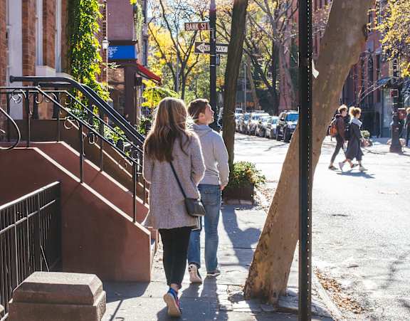 A couple walking down a sidewalk with a "No Parking Anytime" sign.