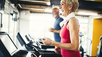 a man and a woman running on a treadmill in a gym
