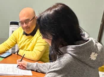 a man and a woman sitting at a table working on paperwork