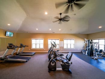 a gym with exercise equipment and a ceiling fan