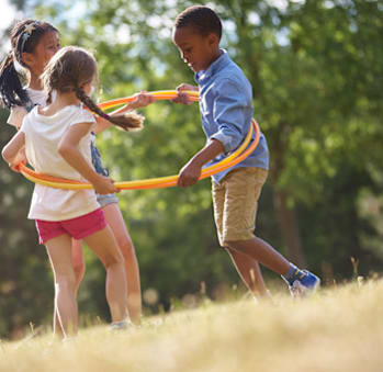 a group of children playing with hula hoops in a field