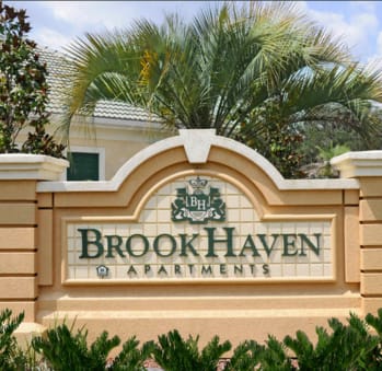 a sign for brookhaven apartments with palm trees in the background