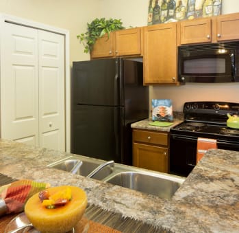 a kitchen with a black refrigerator freezer next to a stove top oven