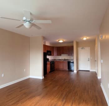 a living room with a ceiling fan and a kitchen in the background