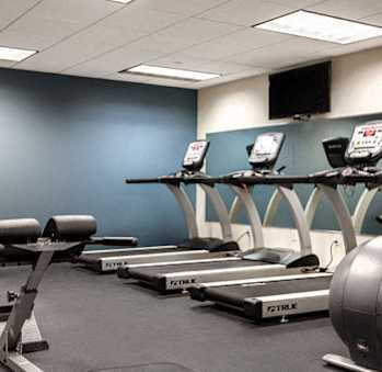 A gym with treadmills and a television mounted on the wall.